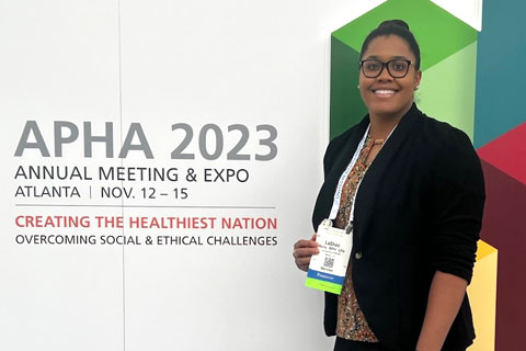 LaShae Rolle standing by APHA 2023 annual meeting and expo sign