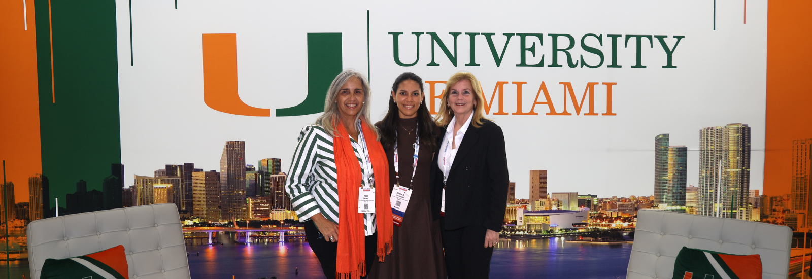 Staff and alumna standing in front of UM's display booth