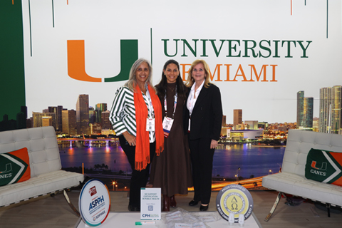 Staff and alumna standing in front of UM's display booth