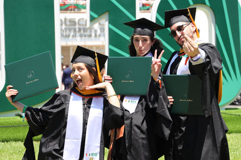 Alumni at graduation celebrate with a pose
