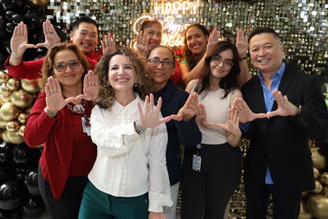 DPHS faculty and staff in front of Happy Holidays neon sign