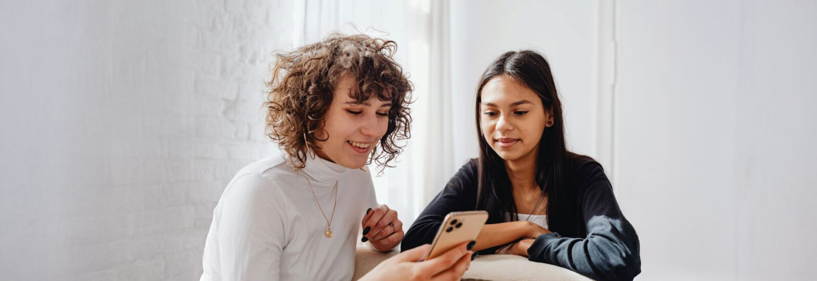 Two women smiling while viewing a mobile phone