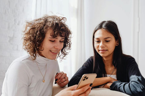 Two women smiling while viewing a mobile phone