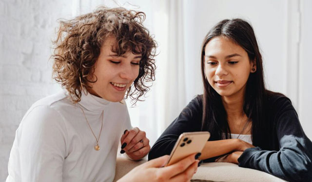 Two women smiling while viewing a mobile phone