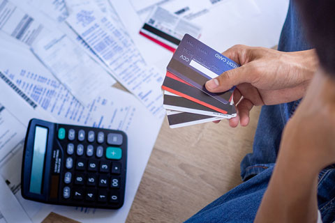 bills, a calculator and a person holding credit cards  