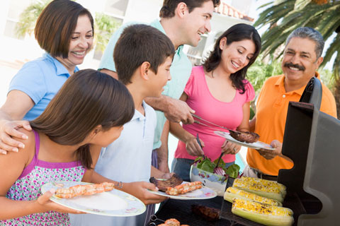 Family smiling by a BBQ grill 