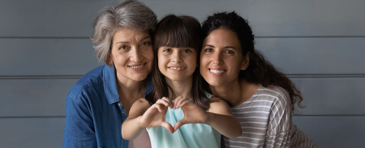 Family hugging and child does a heart symbol with her hands