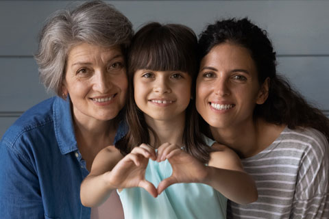 Family hugging and child does a heart symbol with her hands
