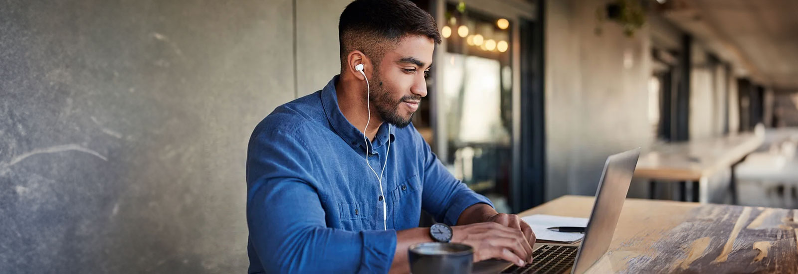 A person sitting with headphones on and looking at a laptop computer