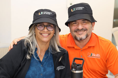 UM staff wearing matching hats and smiling together