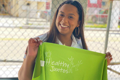 Member of Health eLifestyles Lab smiling while holding a promotional towel